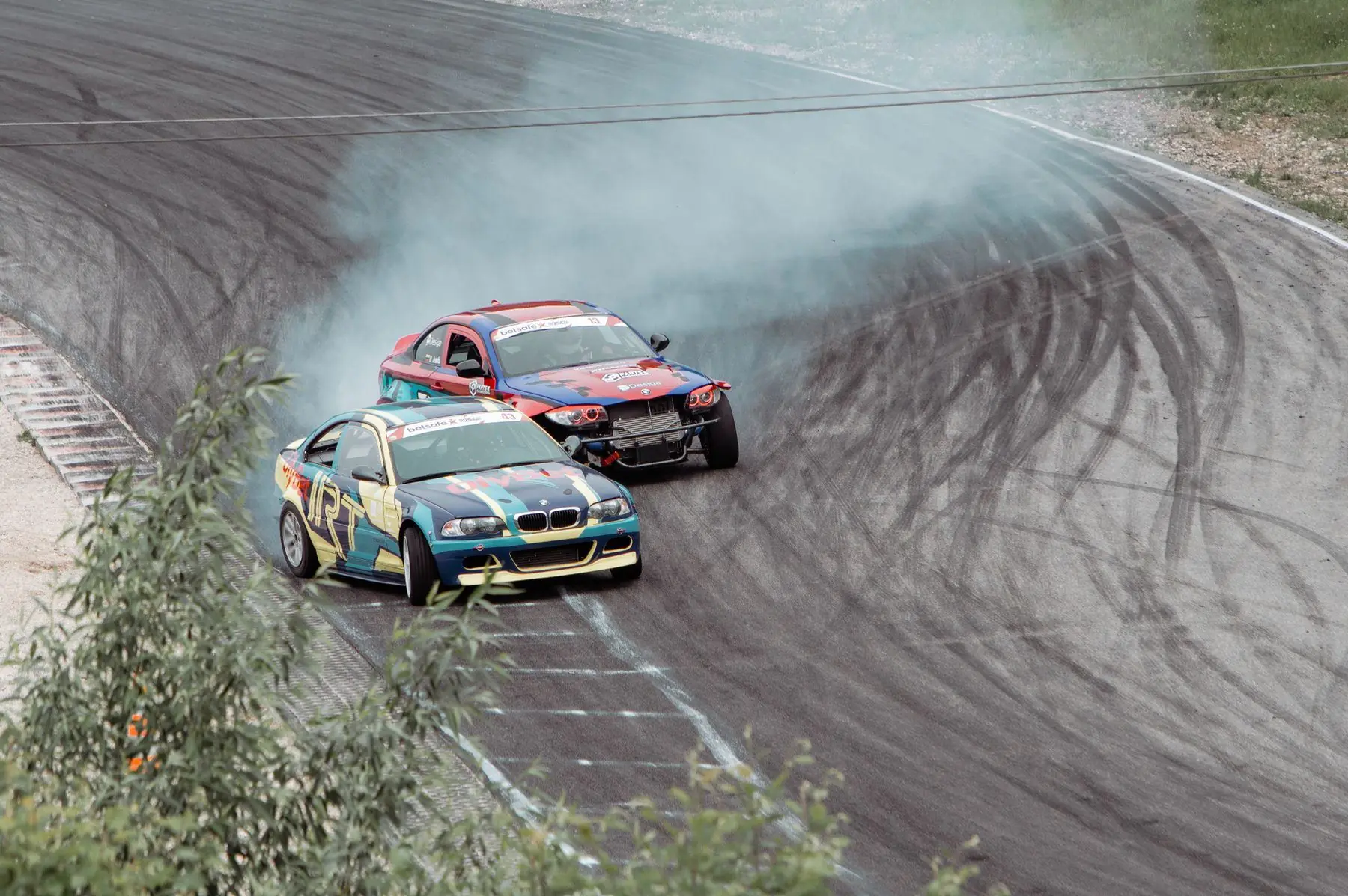 Twee auto's driften met rookontwikkeling door een bocht